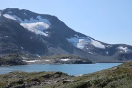 Liten botnbre (til venstre)  ved Fanaråken sett fra Sognefjellsveien i 2019. Botnen er fremdeles ganske grunn, og på grensen til å kalles en botn. Til høyre er en liten bre som ligger i en enda grunnere forsenkning. Denne er klassifisert som en dalsidebre. Sogn og Fjordane.
