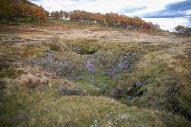 Bildet viser forsenkninger i landskapet (doline), delvis overdekt med løsmasser men bart fjell er også synlig. Denne har også elementer av løsmassedoline, men løsmassene er delvis transportert gjennom karstakviferen og ut av området. Steinugleflåget, Rana, Nordland.
