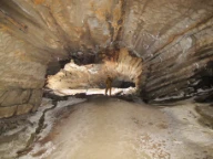 Karstgrotte, golvet dekt med løsmasser og spredt dryppstein utfelt langs sprekker i tak. Fauske, Nordland.
